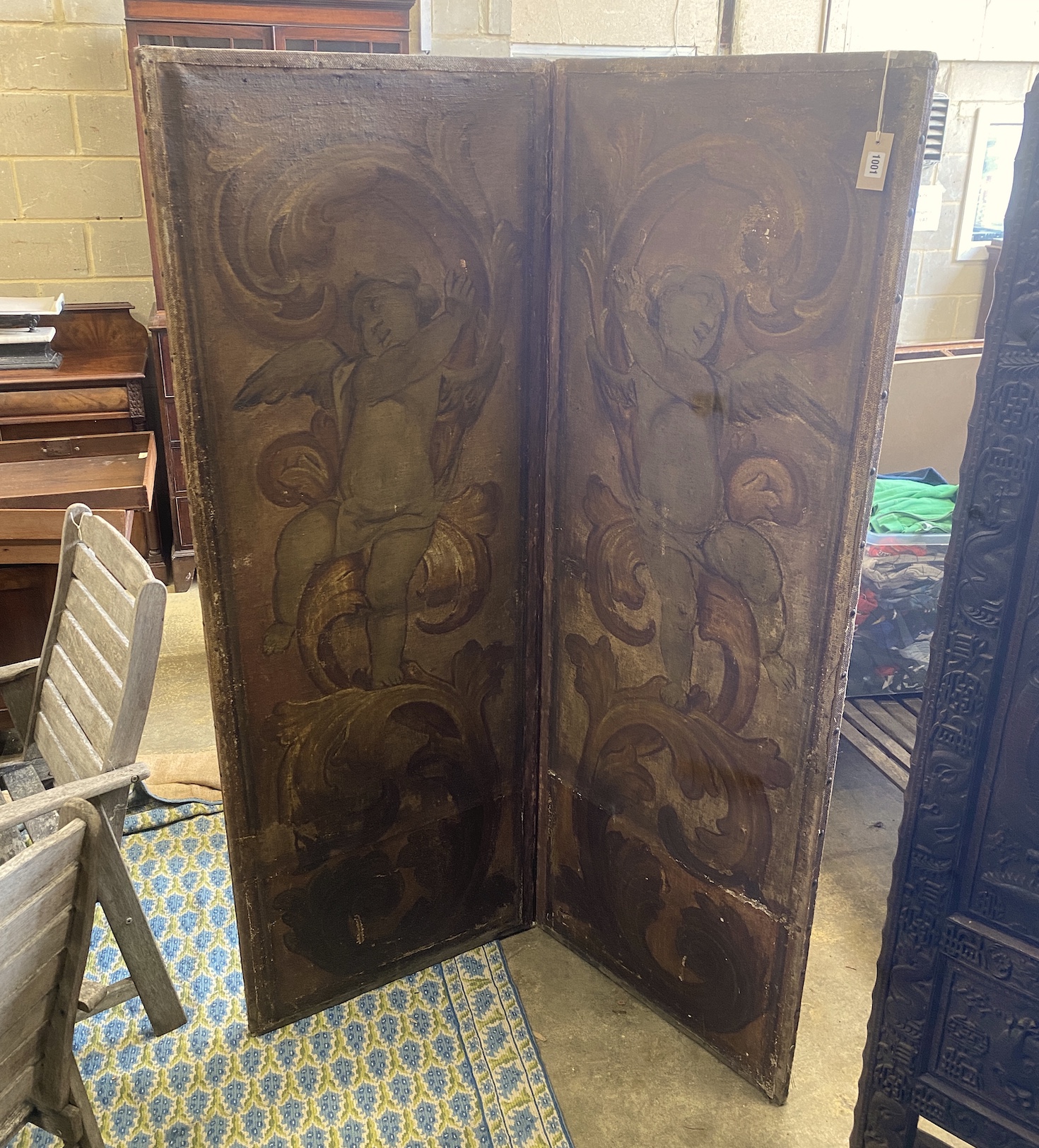 A Victorian painted canvas two fold dressing screen decorated with cherubs amongst scrolls, each panel width 66cm, height 184cm